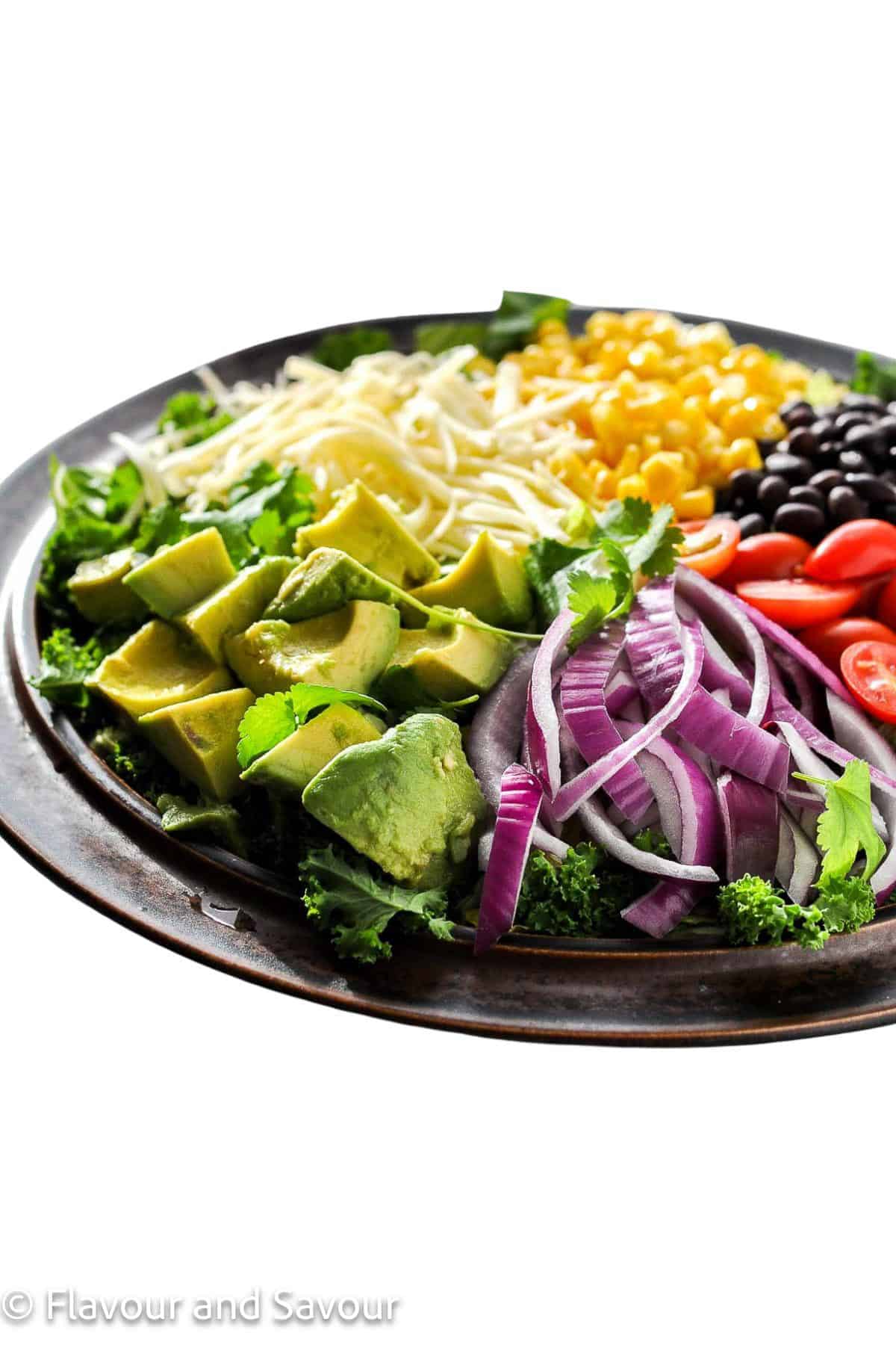 A brown stoneware platter with ingredients for chopped chicken taco salad.