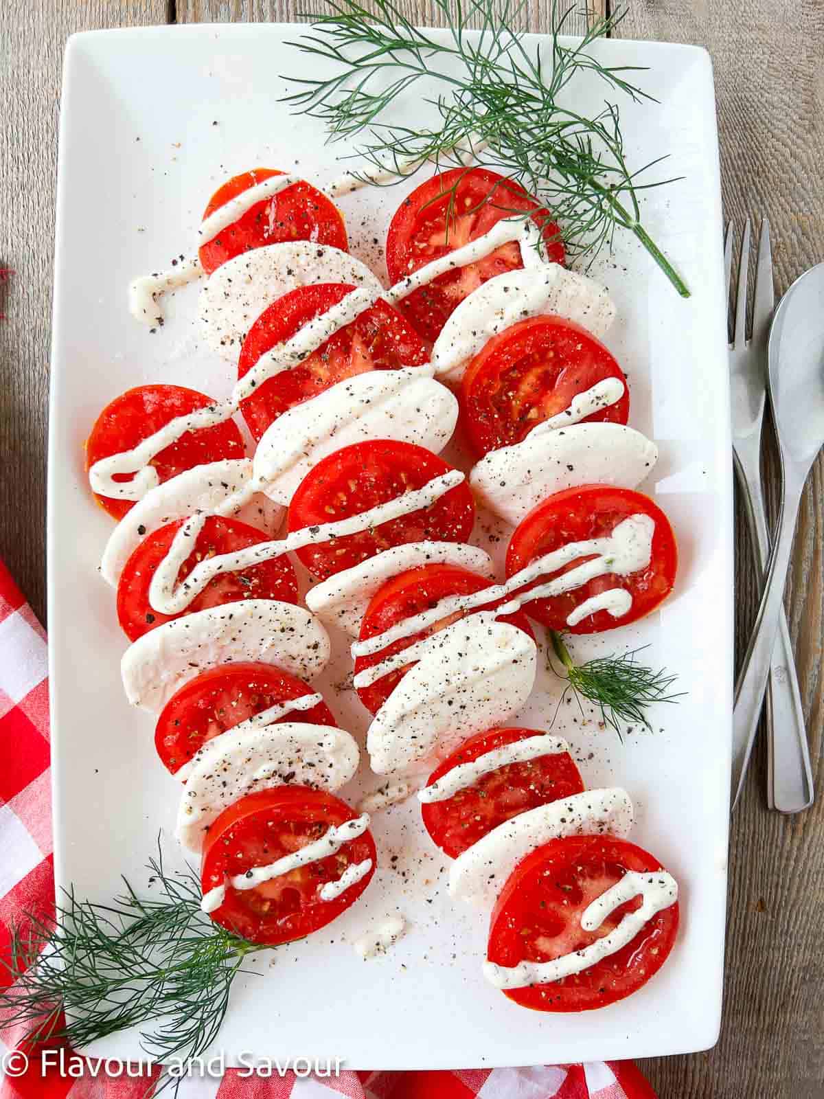 A rectangular platter with Dill Caprese Salad and sprigs of fresh dill.