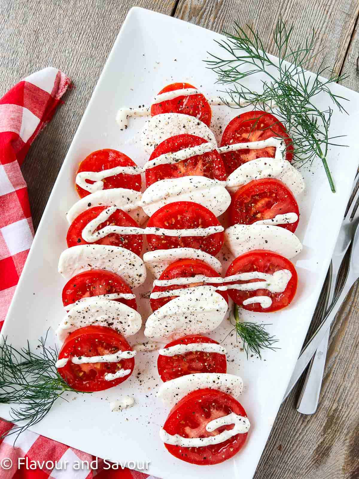 Dill Caprese Salad on a platter sprinkled with freshly ground black pepper and sea salt.