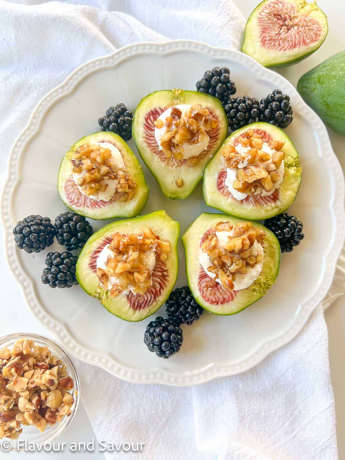 Overhead view of a plate with fig halves topped with goat cheese, maple-glazed walnuts and honey.