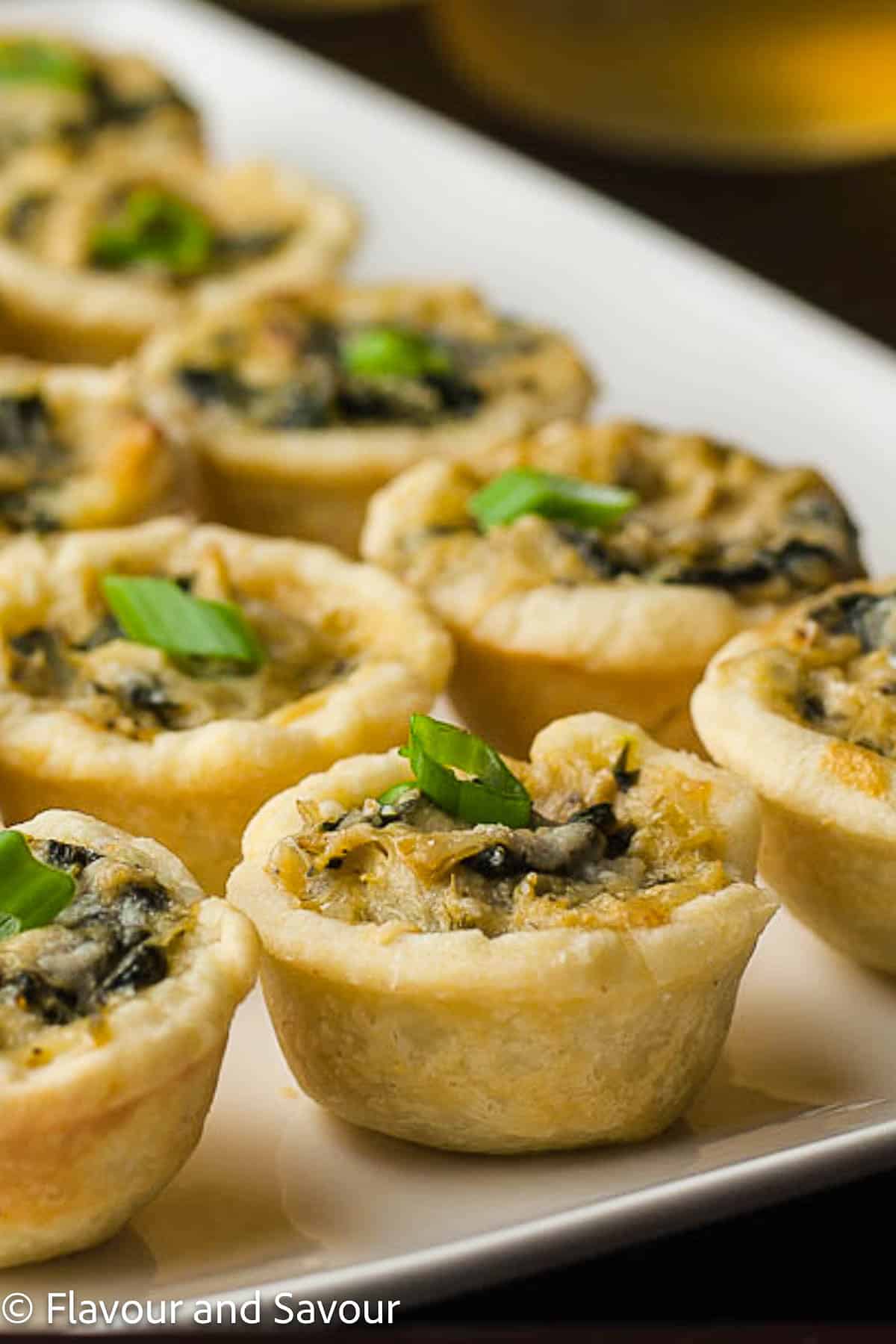 Closeup view of mini spinach artichoke tarts.