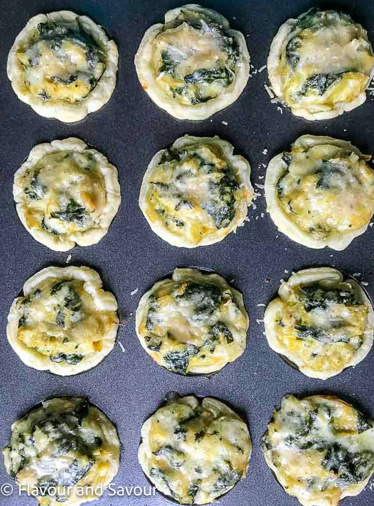 Tart shells filled with spinach artichoke filling.