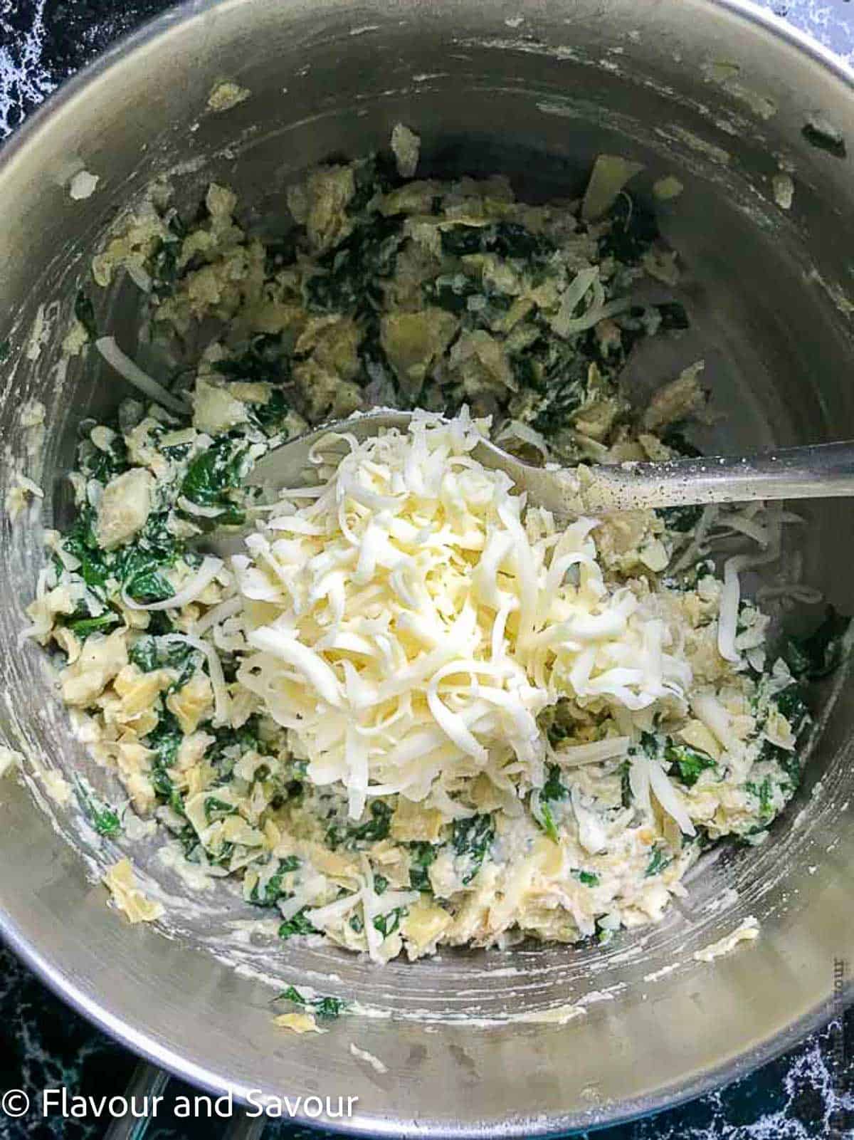 Stirring artichokes, spinach and cheese in a skillet.