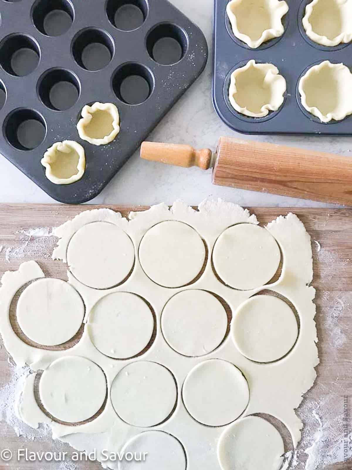 Pastry circles for tarts with a rolling pin and tart tins.