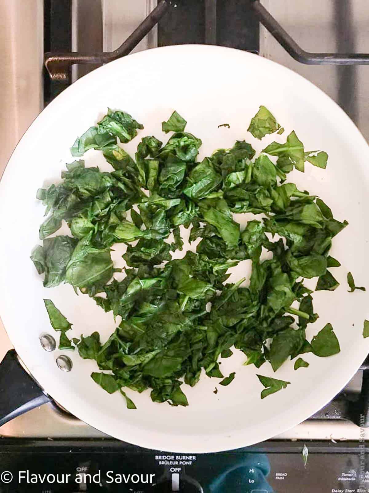 Wilted spinach leaves in a skillet.