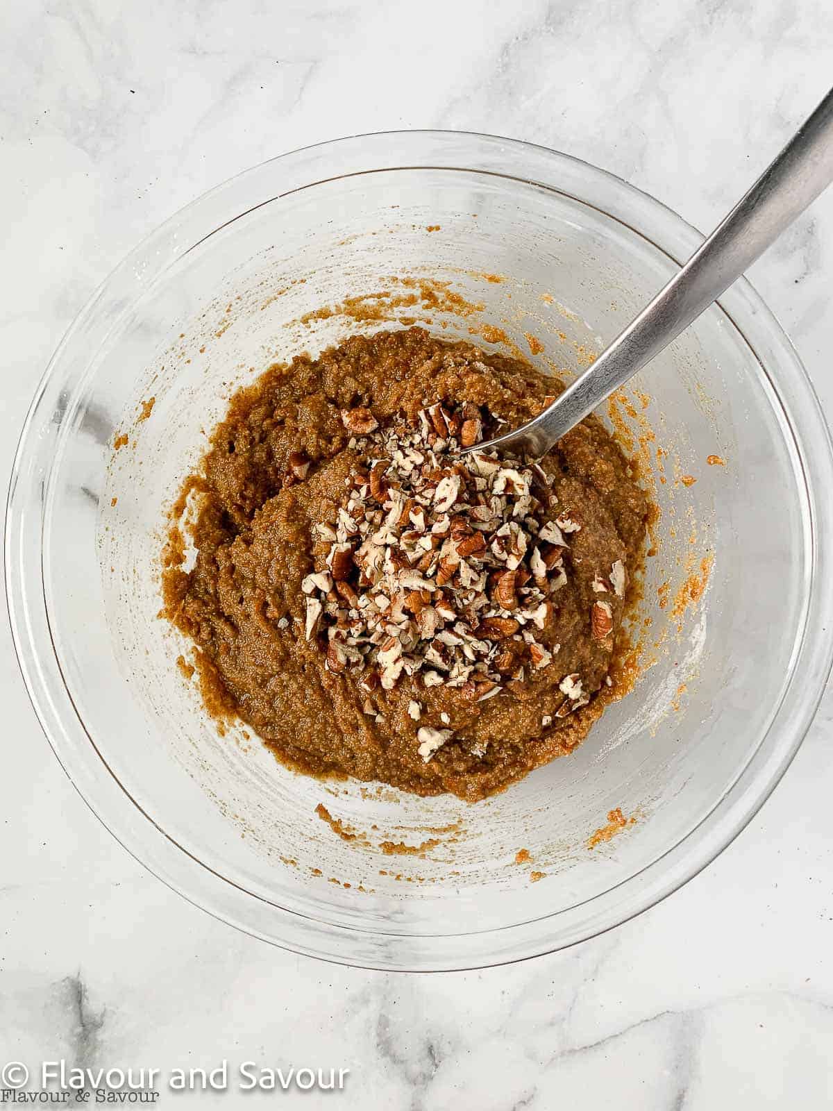 Adding chopped pecans to pumpkin coffee cake batter.