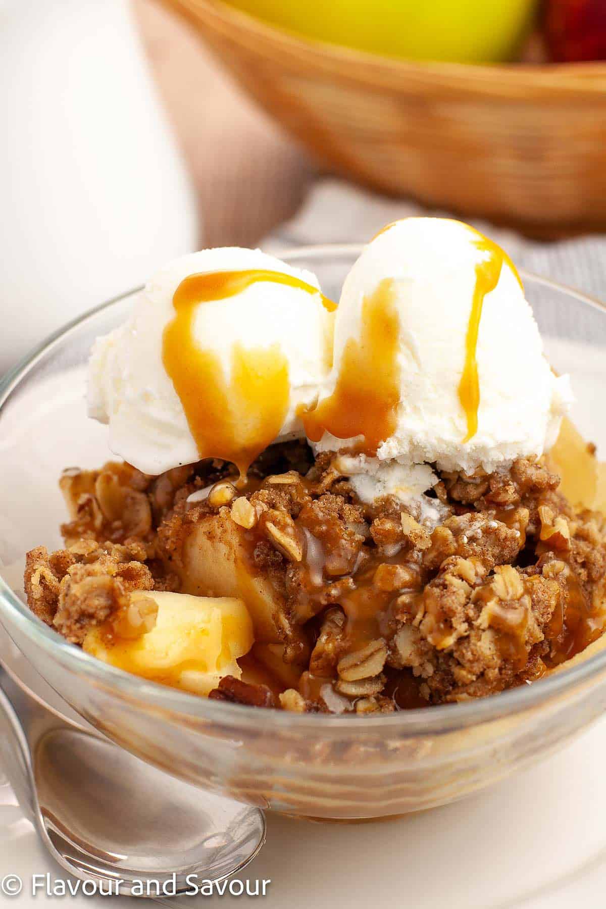 A bowl of gluten-free apple pecan crisp topped with ice cream and caramel sauce.
