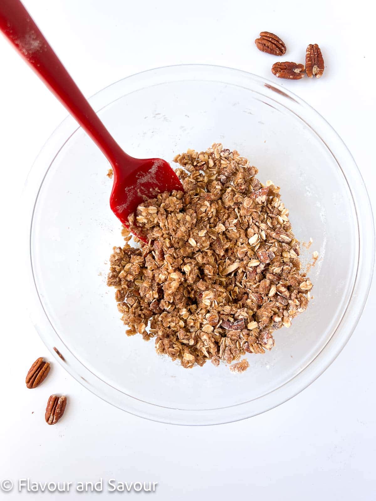 Ingredients for fruit crisp topping in a glass bowl with a spatula.