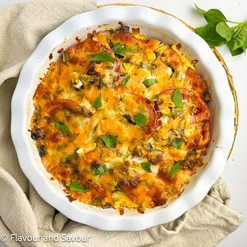 Square image of a pie dish with baked crustless tomato pie.