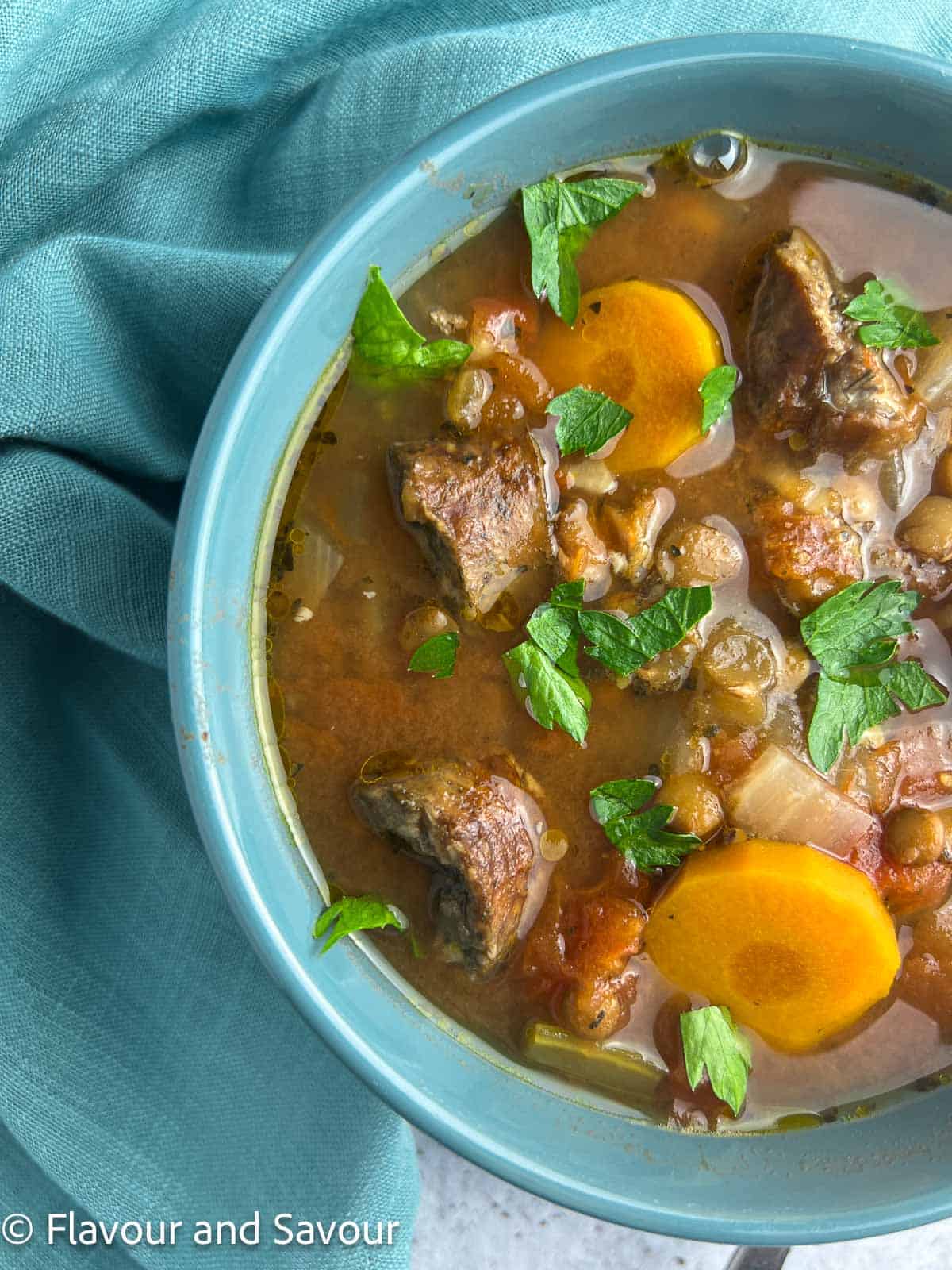 A bowl of stew with lentils, vegetables and chicken sausage.