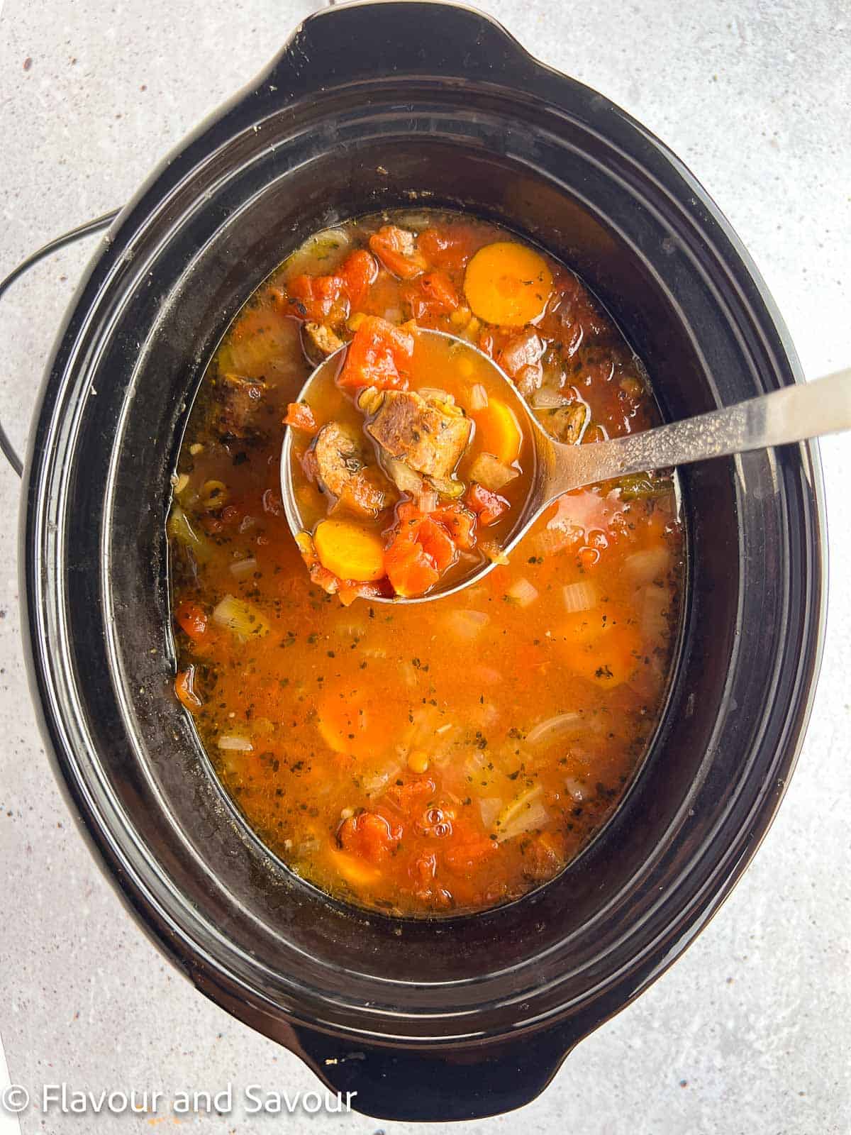 Lentil and sausage stew, cooked, in a slow cooker.