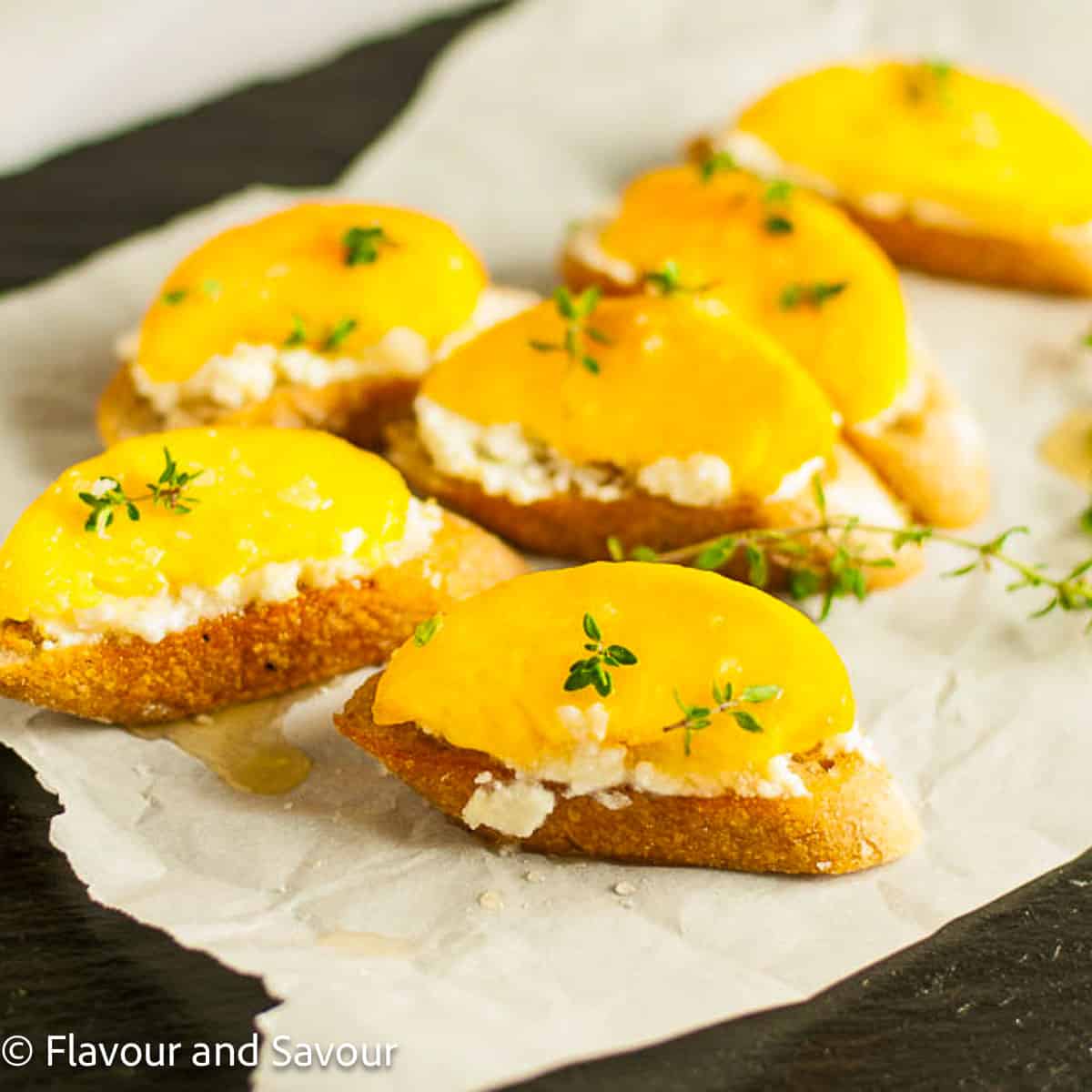 Peach crostini garnished with fresh thyme leaves.