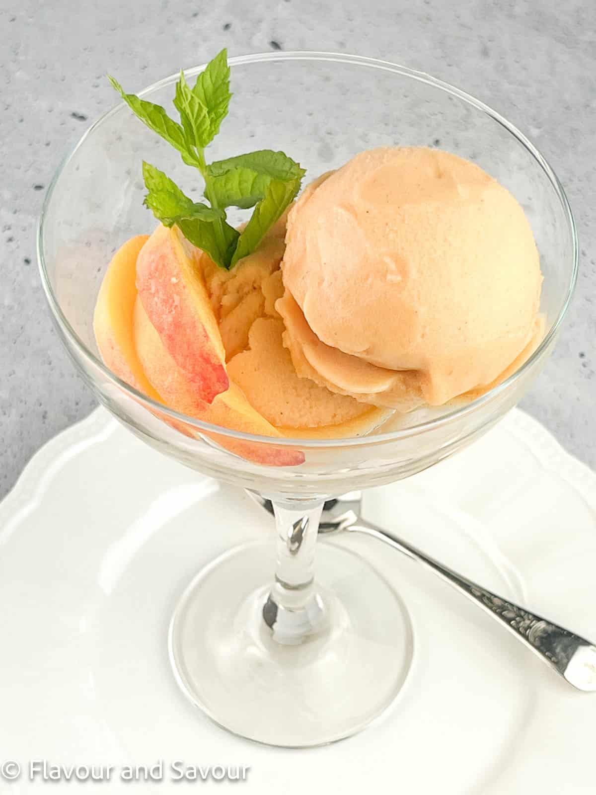 Peach ginger sorbet in a dessert glass with a spoon.