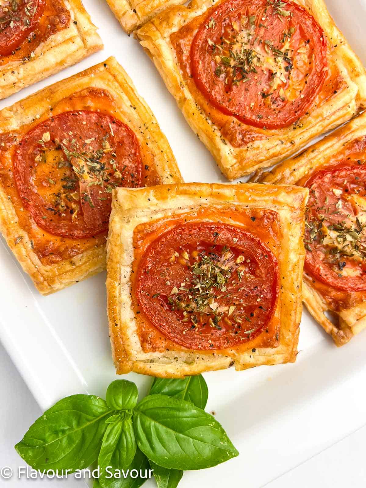 Closeup view of puff pastry tart with cheese and tomato slices.