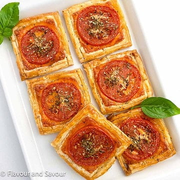 Square image of puff pastry pizza tarts on a serving plate.