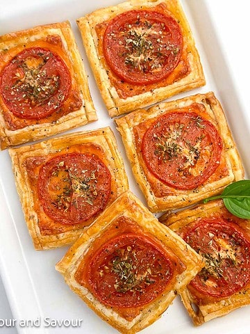 Square image of puff pastry pizza tarts on a serving plate.