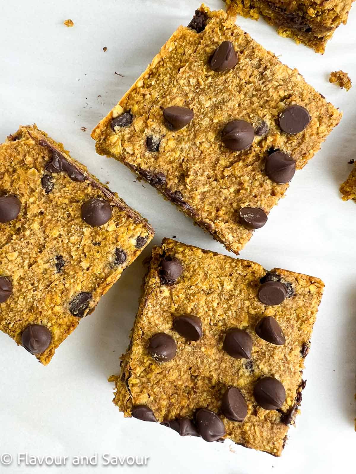 Closeup view of 3 pumpkin oat bars topped with chocolate chips.