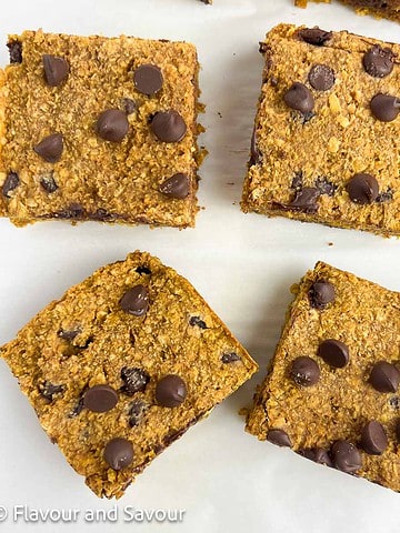 Square image of four pumpkin oat squares with chocolate chips.