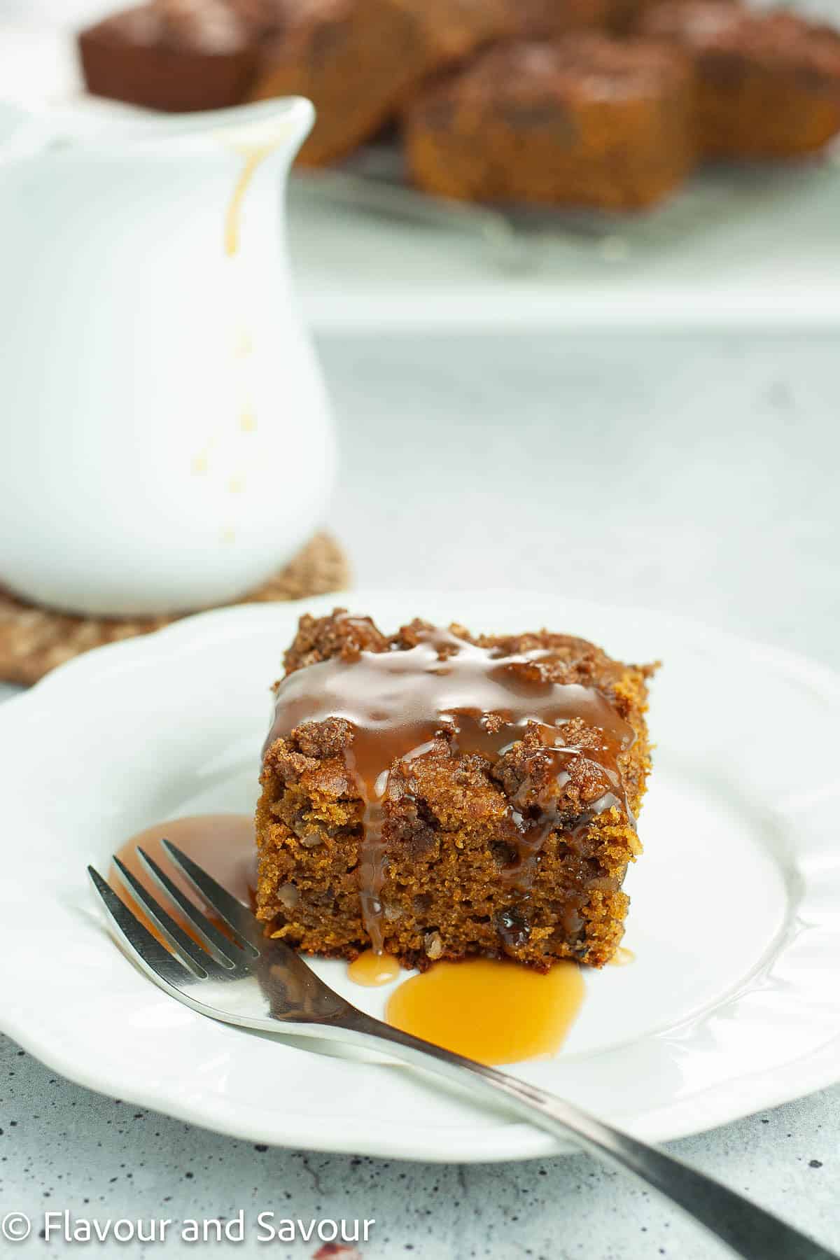 A slice of pumpkin pecan coffee cake with caramel sauce on a plate.