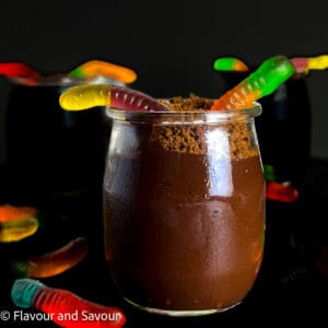 A small dessert glass with chocolate pudding and gummy worms.