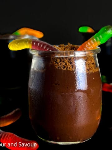 A small dessert glass with chocolate pudding and gummy worms.