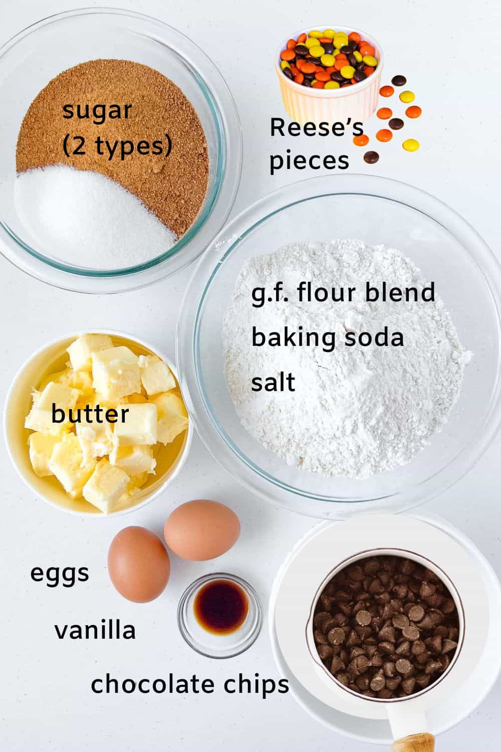 Labelled ingredients for gluten-free Halloween Reese's Pieces chocolate chip cookies: sugar, butter, eggs, vanilla, gluten-free flour, baking soda, sea salt, chocolate chips, Reese's pieces.