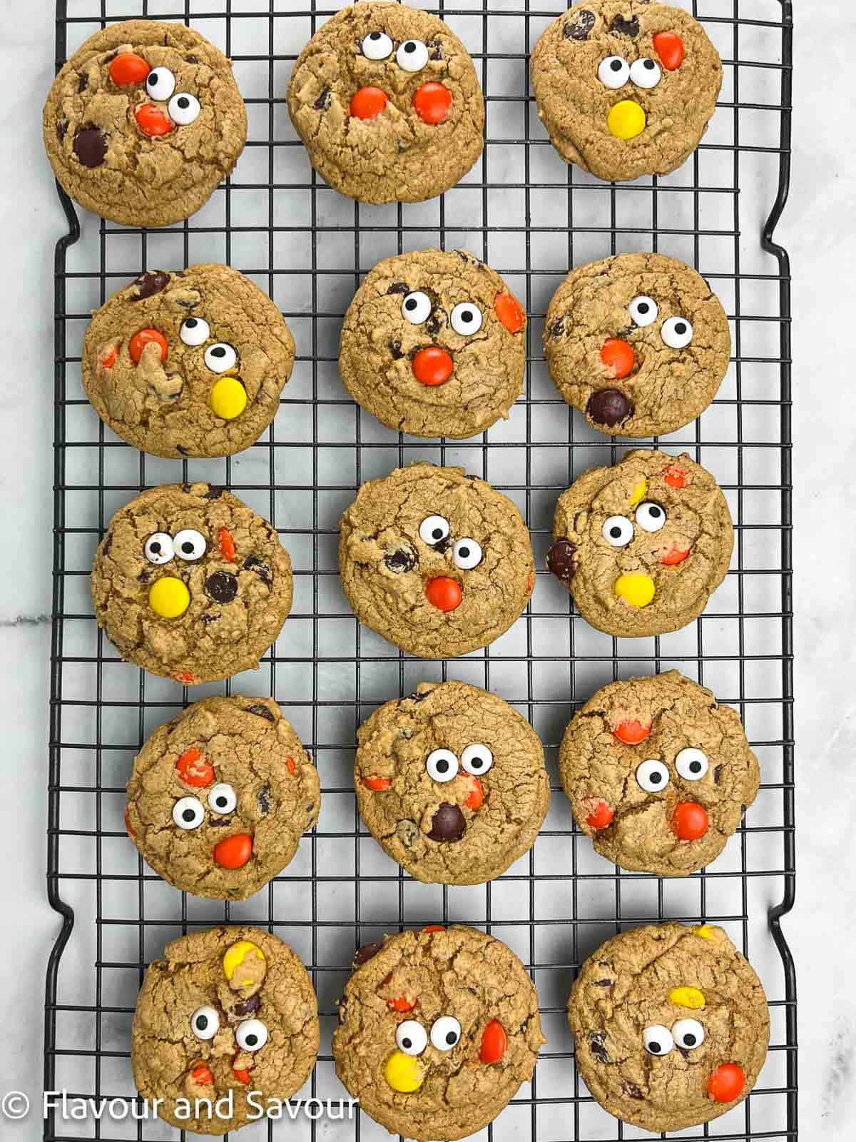 Gluten-free Reese's Pieces Cookies with candy eyes on a wire rack.