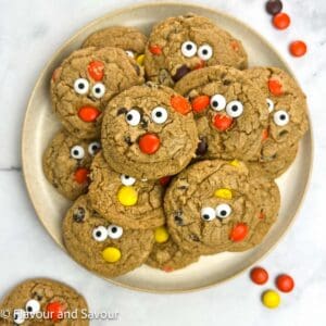 Gluten-free Reese's Pieces Halloween Cookies with edible eyes stacked on a plate.