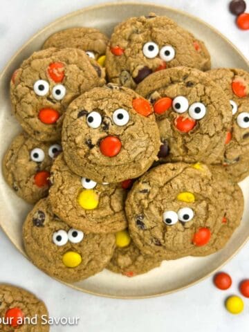 Gluten-free Reese's Pieces Halloween Cookies with edible eyes stacked on a plate.