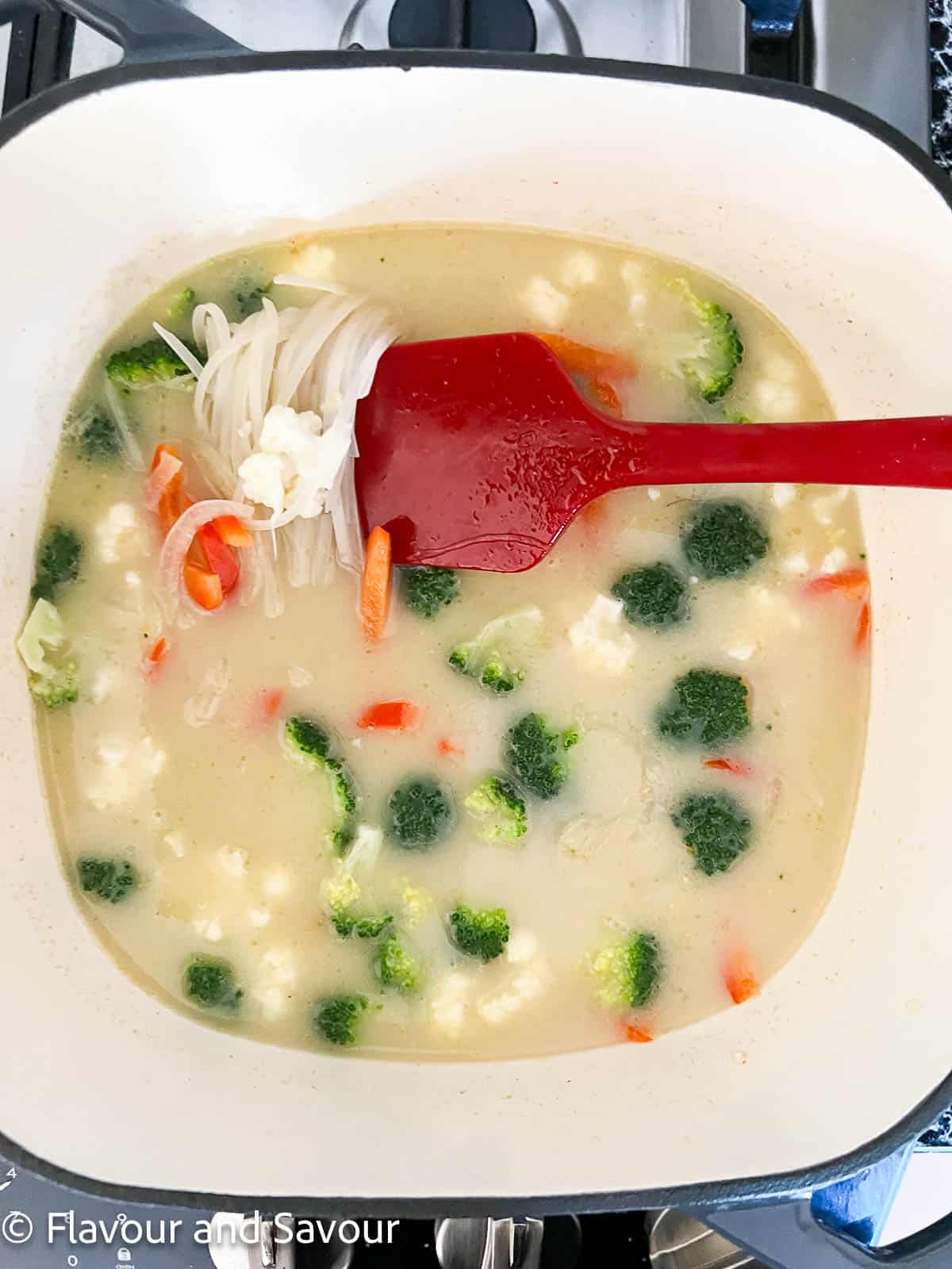 Step 3 to make Thai chicken noodle soup: add vegetables and noodles.