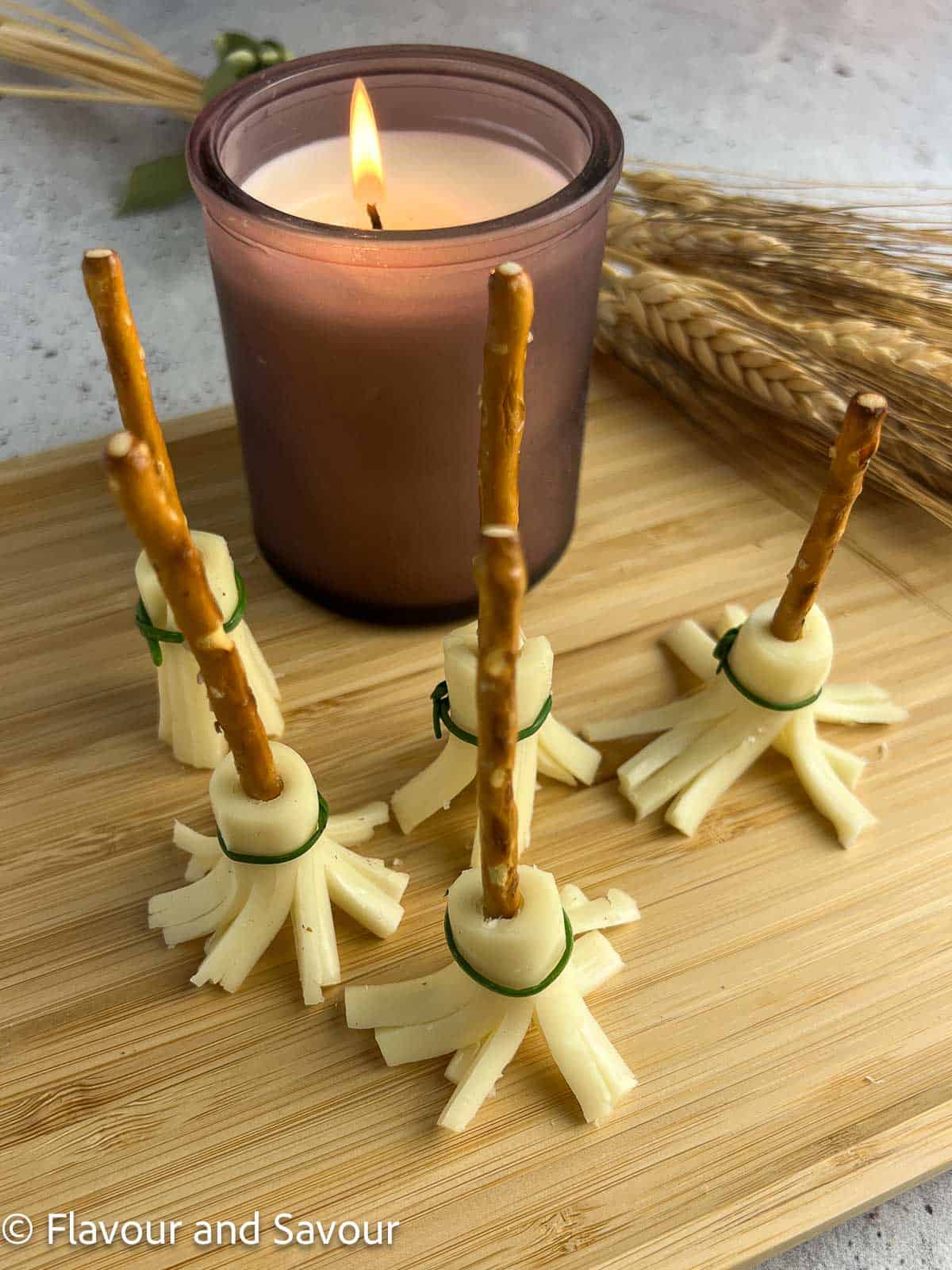 Witches' broomsticks snacks standing upright next to a candle.