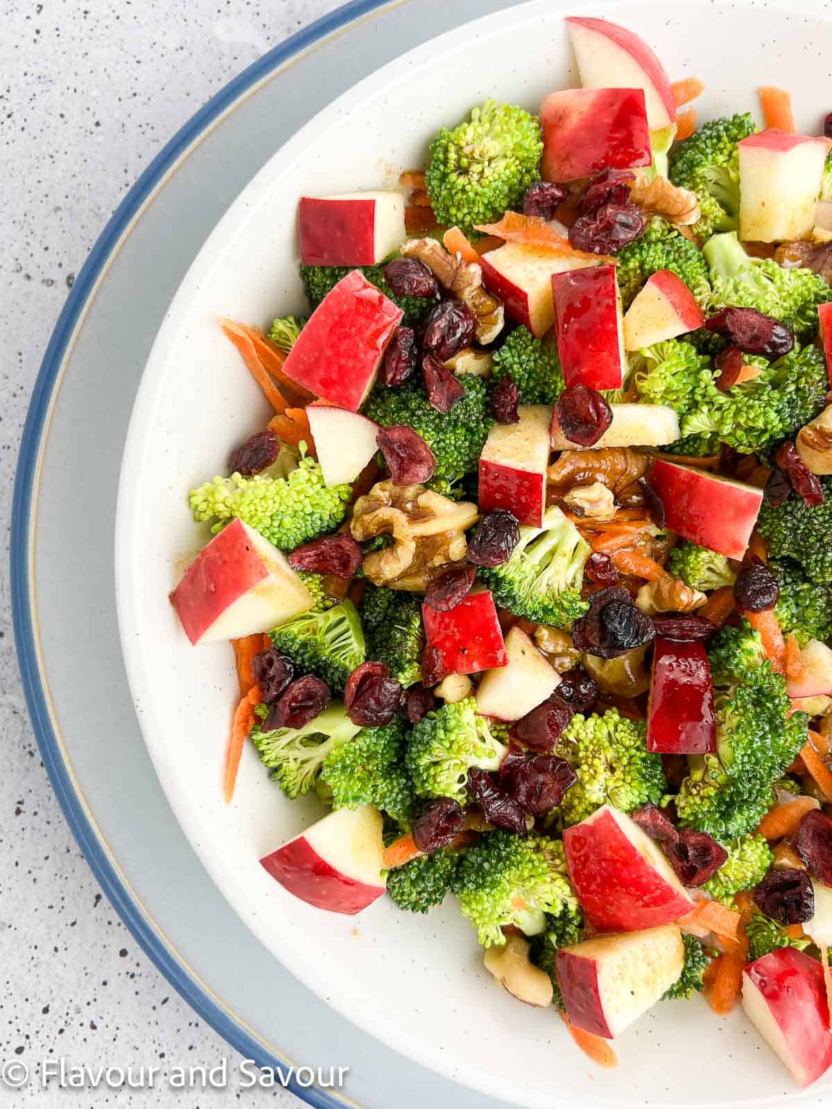 Extreme closeup view of broccoli apple salad in a shallow white bowl.