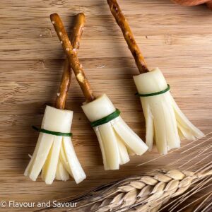 Cheese and pretzel witch broomsticks tied with chives.