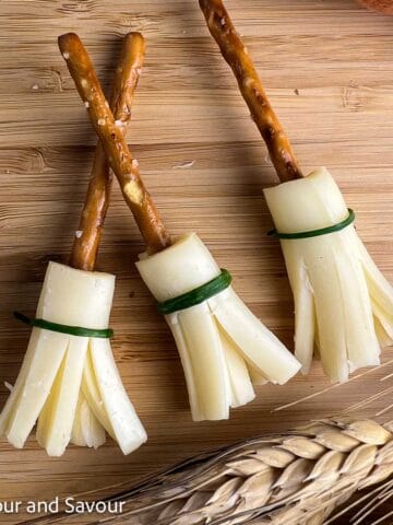 Cheese and pretzel witch broomsticks tied with chives.