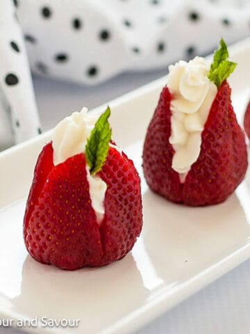 Strawberries stuffed with goat cheese and garnished with a mint leaf.