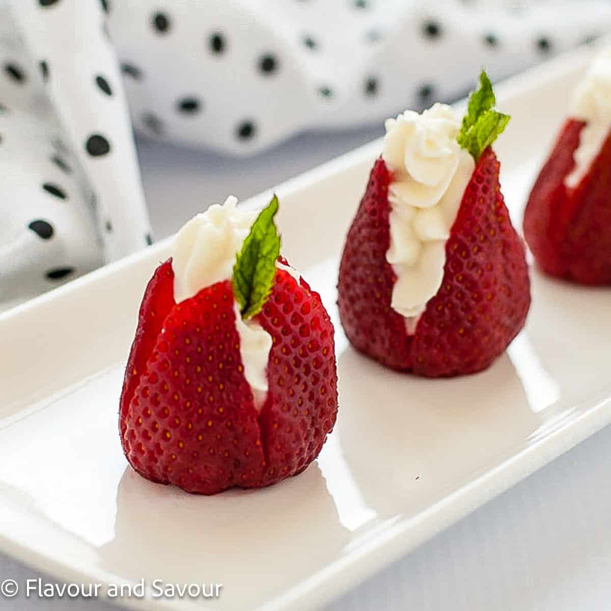 Strawberries stuffed with goat cheese and garnished with a mint leaf.