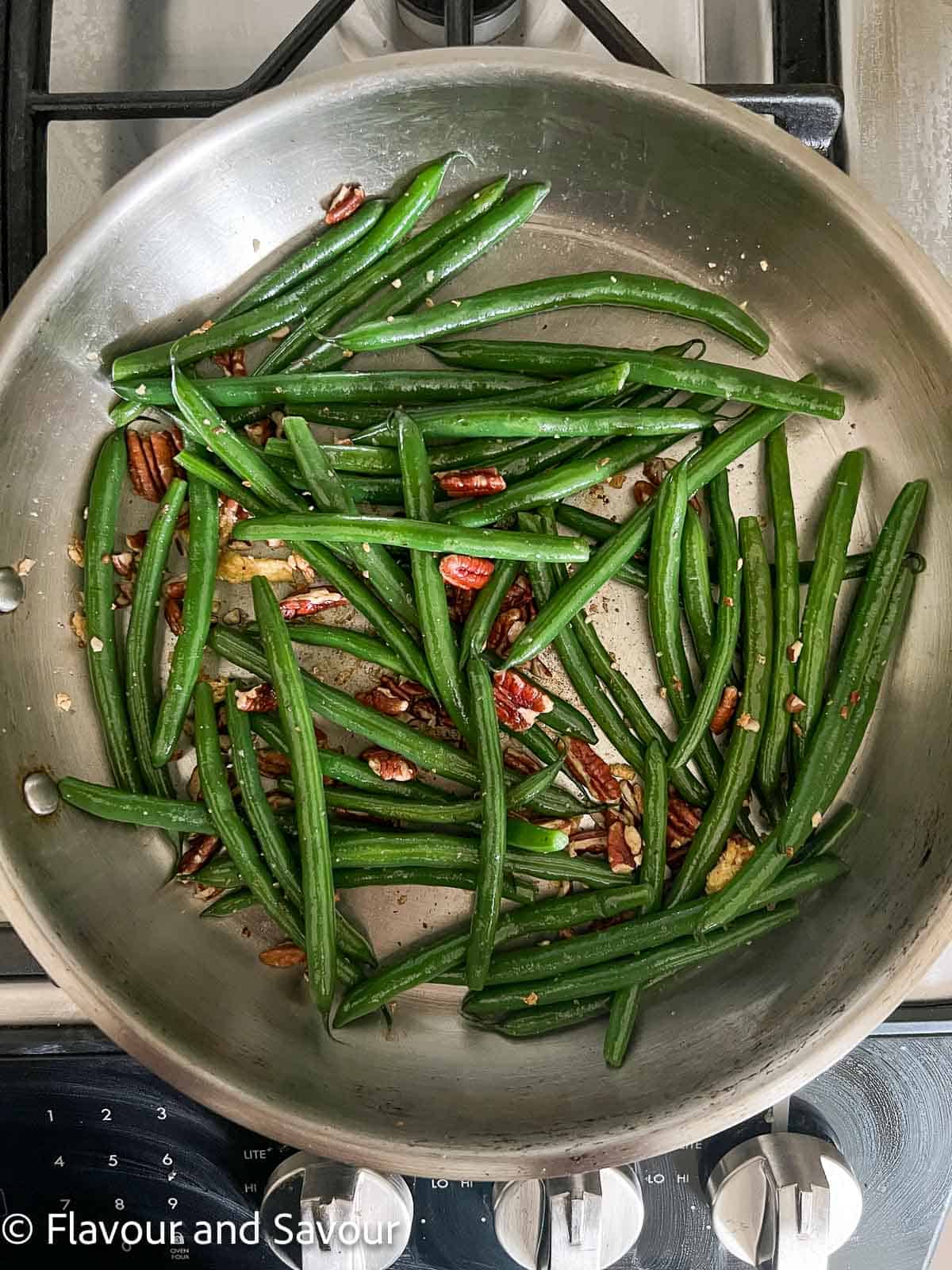 Garlic green beans with pecans in a skillet.