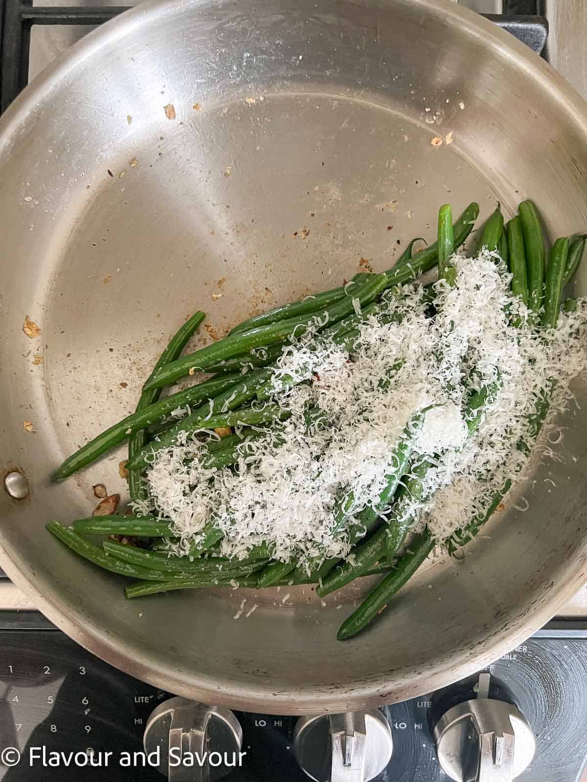 Garlic green beans in a skillet with finely grated parmesan.