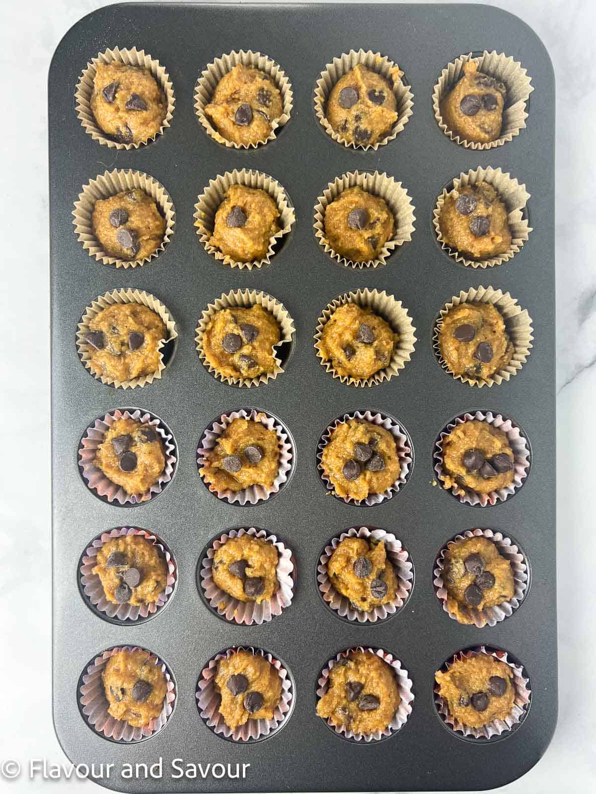 Mini chocolate chip pumpkin muffin batter in muffin tin.