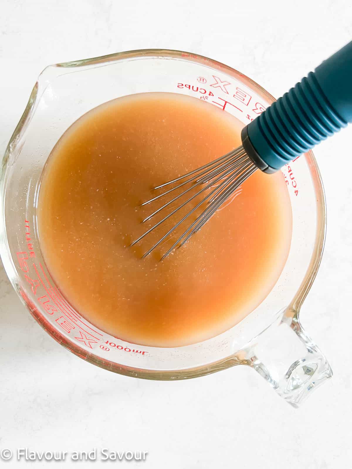 Whisking vegetable broth and miso in a 4 cup Pyrex measuring cup.