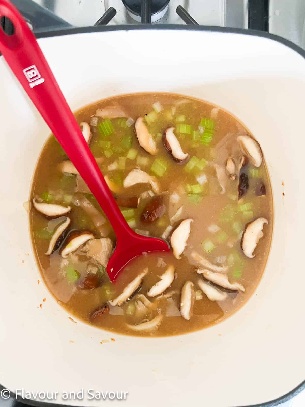 Adding miso broth to sautéed vegetables to make miso noodle soup.