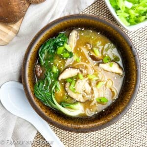 Miso noodle soup with baby bok choy, shiitake mushrooms, oyster mushrooms, garnished with green onions and sesame seeds.