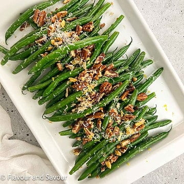 Sauteed garlic parmesan green beans with pecans on a serving dish.