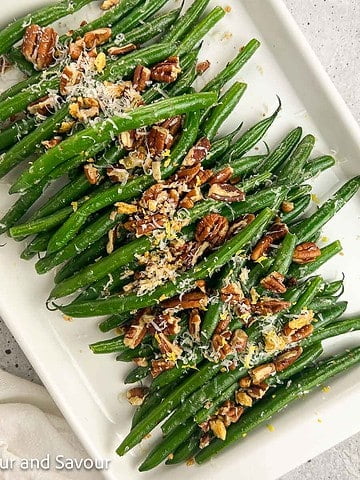 Sauteed garlic parmesan green beans with pecans on a serving dish.