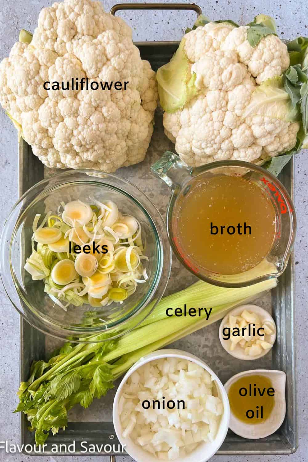 Labelled ingredients for cauliflower soup: cauliflower, leeks, broth, celery, garlic, onion, and olive oil.
