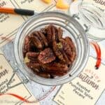 Overhead view of a small jar of roasted pumpkin spice pecans with printable gift tags beside it.