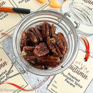 Overhead view of a small jar of roasted pumpkin spice pecans with printable gift tags beside it.