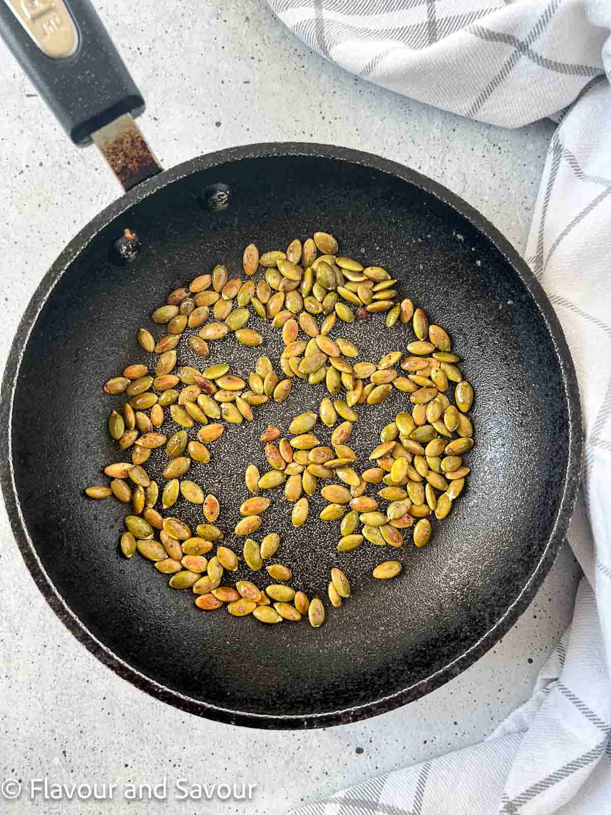Toasted pumpkin seeds in a skillet.