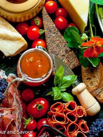 An Italian style antipasto platter with a variety of cured meats, cheese, dips and vegetables.