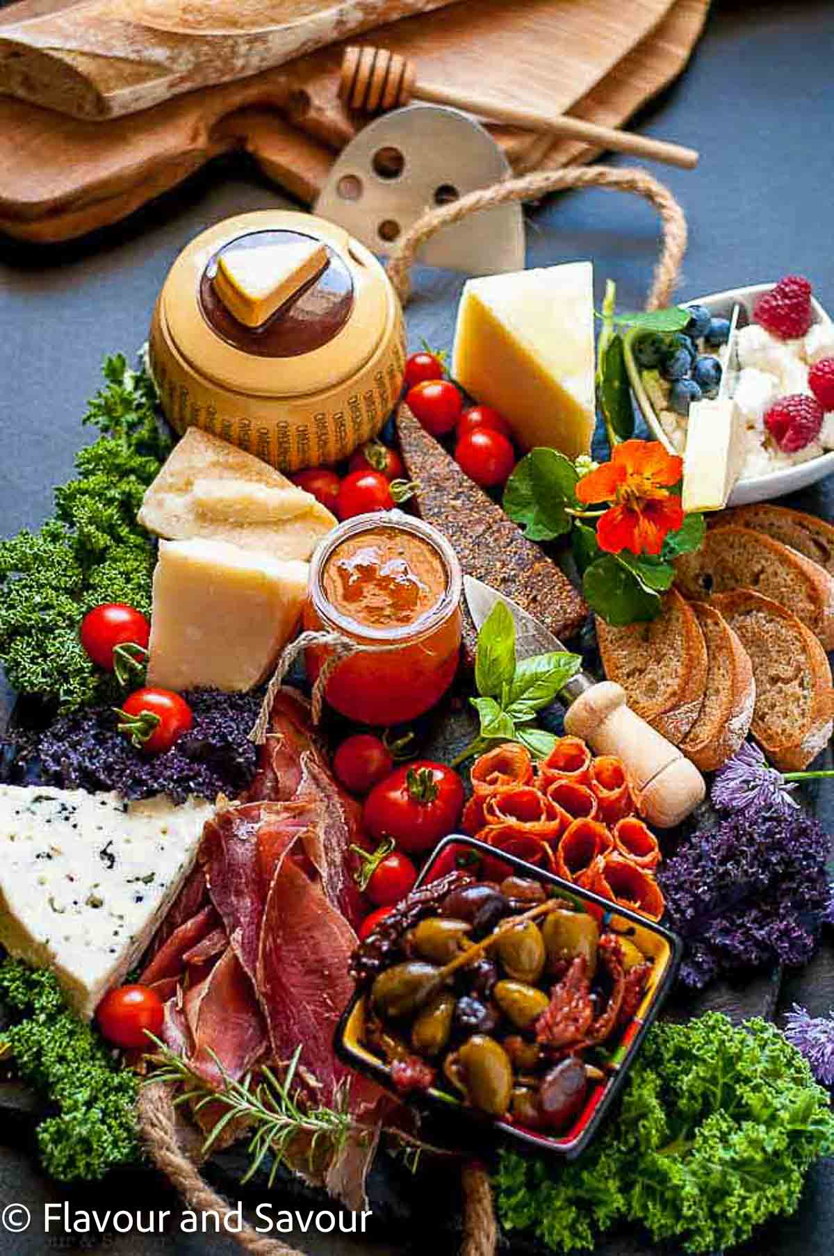 An antipasto platter with meats, olives, cheese, dips and vegetables.